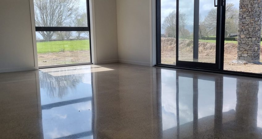 photo of salt and pepper polished concrete floor in lounge area looking towards windows with reflection