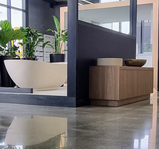 Salt and pepper ground polished floor at Harrison Bloy plumbing showroom showing a bath and vanities in distance